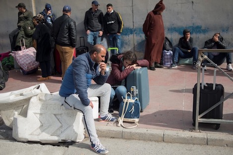 People wait to cross the Spanish border with Morocco in Ceuta on March 13, 2020. - Morocco suspended air and sea links with France and Spain, and closed its border with two Spanish North African enclaves, to prevent the spread of coronavirus, officials said. Rabat's decision to close frontiers around Ceuta and Melilla shuts the only land border between Africa and the European Union. (Photo by JORGE GUERRERO / AFP)