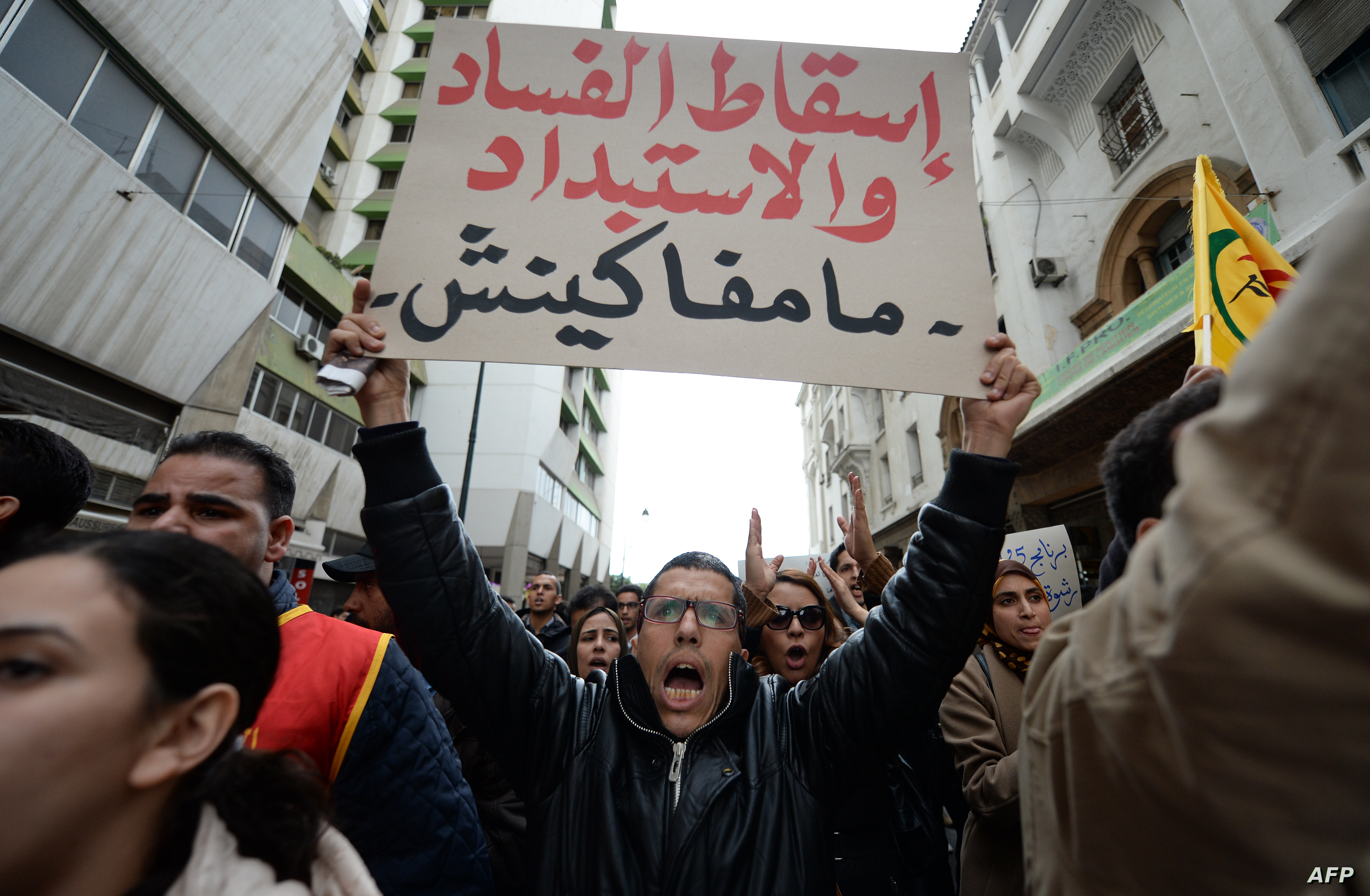 A Moroccan supporter of the February 20 pro-reform movement holds a placard meaning in Arabic "Stop corruption. We will not give up" during a demonstration to mark the fifth anniversary the movement's creation, on February 20, 2016 in the capital Rabat. Several hundred protesters took part in the demonstration to mark the anniversary of the creation of the pro-reform movement, that was born during the Arab Spring, and called for social justice and change. / AFP PHOTO / FADEL SENNA