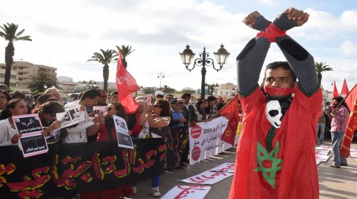 A handcuffed Moroccan protester raises his fists during a demonstration in front the parliament in the capital Rabat on May 25, 2014, demanding the release of activists from the February 20 pro-reform movement who were jailed this week. A court in Casablanca sentenced on Thursday 11 activists from the February 20 group to jail terms of up to one year for violence against police during an unauthorised protest in April. AFP PHOTO / FADEL SENNA / AFP PHOTO / FADEL SENNA