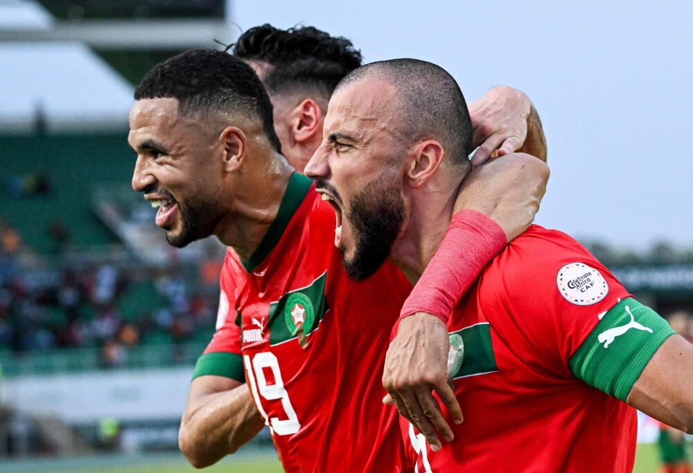 Morocco's defender #6 Romain Saiss (R) celebrates with Morocco's forward #19 Youssef En-Nesyri (C) after scoring his team's first goal during the Africa Cup of Nations (CAN) 2024 group F football match between Morocco and Tanzania at Stade Laurent Pokou in San Pedro on January 17, 2024. (Photo by SIA KAMBOU / AFP)